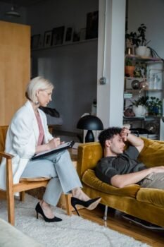 Un conseiller écoute attentivement un patient en détresse dans un environnement de salon moderne.